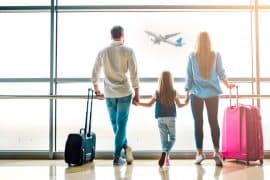 imagem com um homem e uma mulher cada um segurando uma mão de uma menina e na outra m]ao segurando a mala