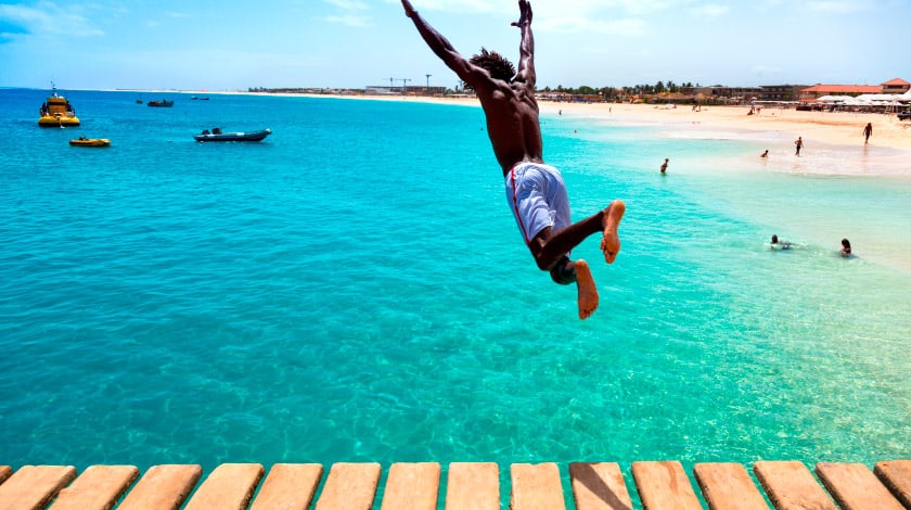Imagem de um homem pulando no mar de Cabo Verde, na África Ocidental.