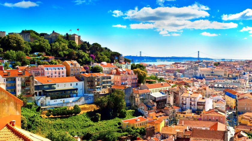 Imagem de cima da cidade de Lisboa, com várias casas e a ponte de fundo