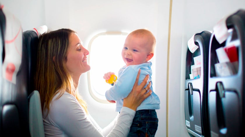 Mulher segurando bebê sorrindo dentro do avião