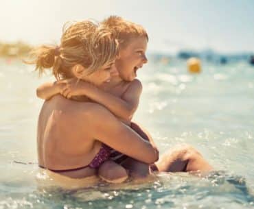 Mãe e filho felizes se abraçando no mar