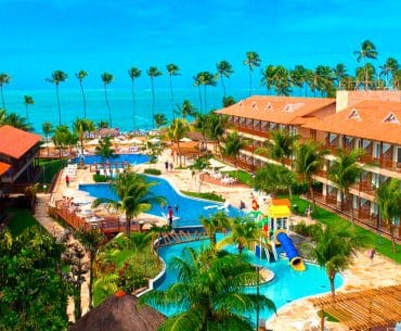 Foto do resort com acomodações, piscina ao centro e praia ao fundo