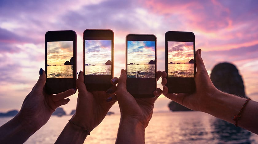 Comparação de celulares registrando a paleta de cores em foto do pôr do sol.