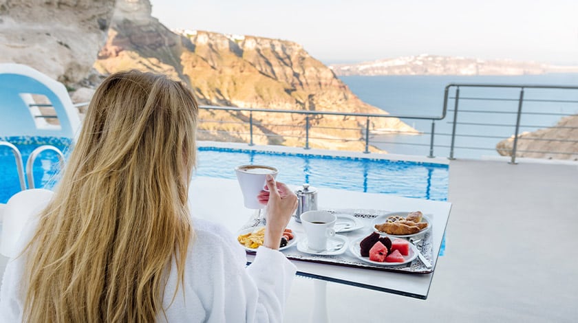 Mulher tomando um café em sua própria companhia, com cenário em frente ao mar