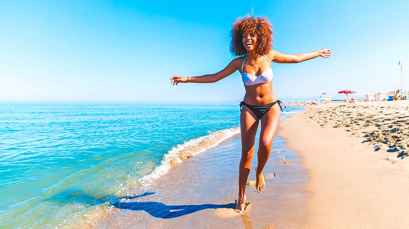 Mulher negra curtindo uma praia em sua própria companhia