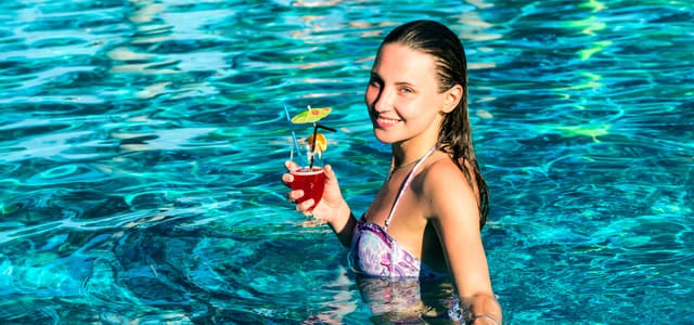 menina tomando drink na piscina