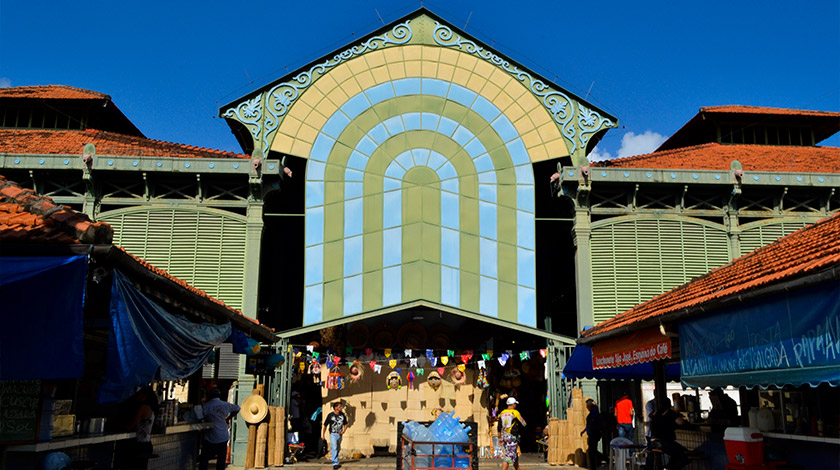 Vista da fachada do galpão do Mercado de São José, com barraquinhas e bandeiras de festa junina